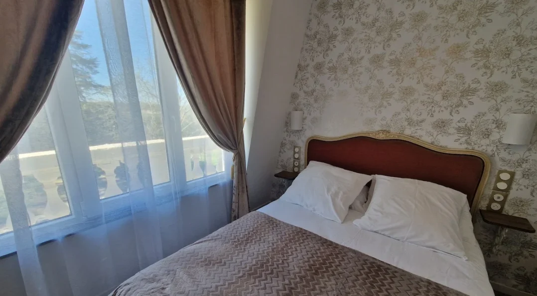 Notre modèle de chambre douillette et lumineuse d'inspiration rétro avec vue sur le parc et mobilier vintage. Tapisserie motif floral délicat