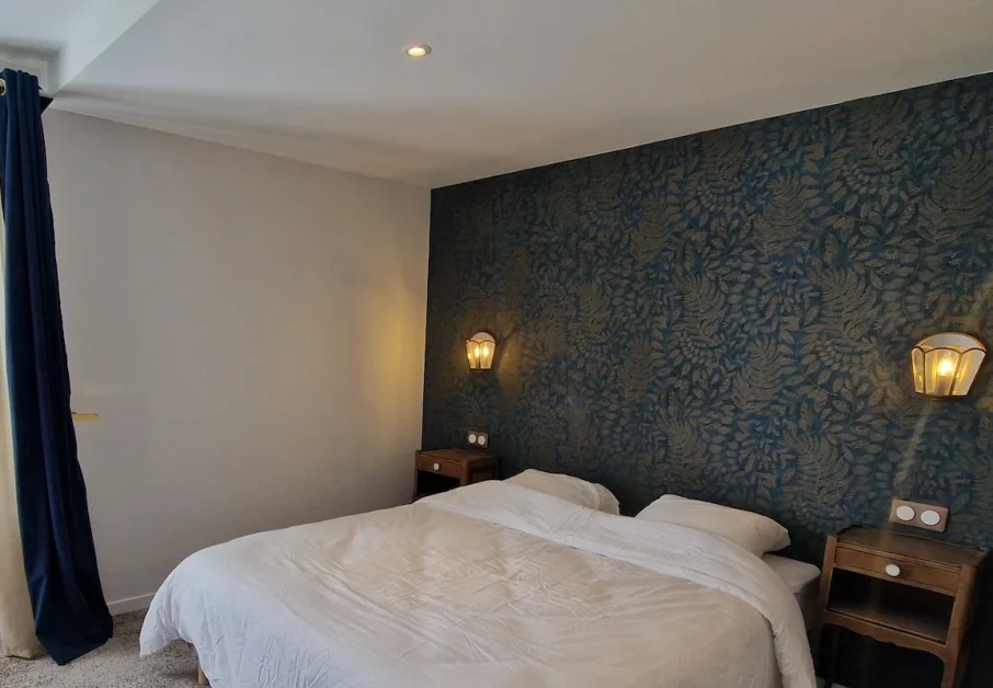 Chambre PMR Bienveillante 1 Une chambre PMR adaptée au Château. Large espace, lit double confortable, vue sur le parc. Tapisserie motif cashmere bleu foncé et beige