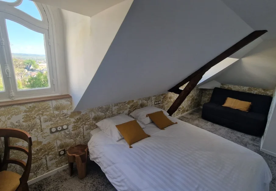 Chambre quadruple château Charmantes 1 Notre modèle de chambre quadruple au château avec vue sur le parc, lit double + canapé-lit, mobilier vintage et tapisserie motif ancien. Ici pièce en soupente