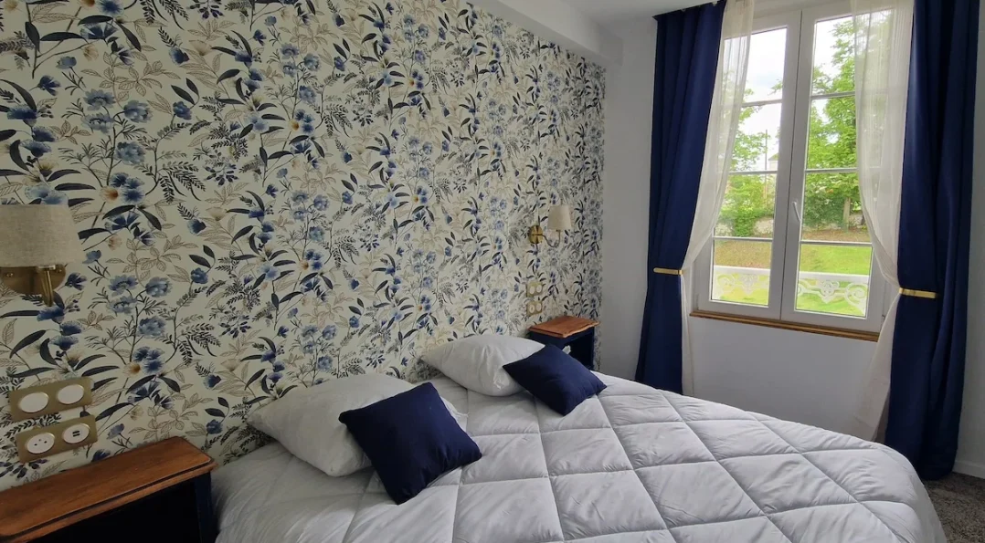 Un exemple de notre chambre triple château avec vue sur le parc. Tapisserie motif ancien, mobilier vintage, lit double confortable et couchage d'appoint. Tonalité générale de la décoration : bleu marine
